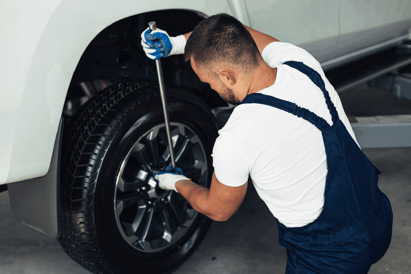 High angle male mechanic changing car wheels<br />
