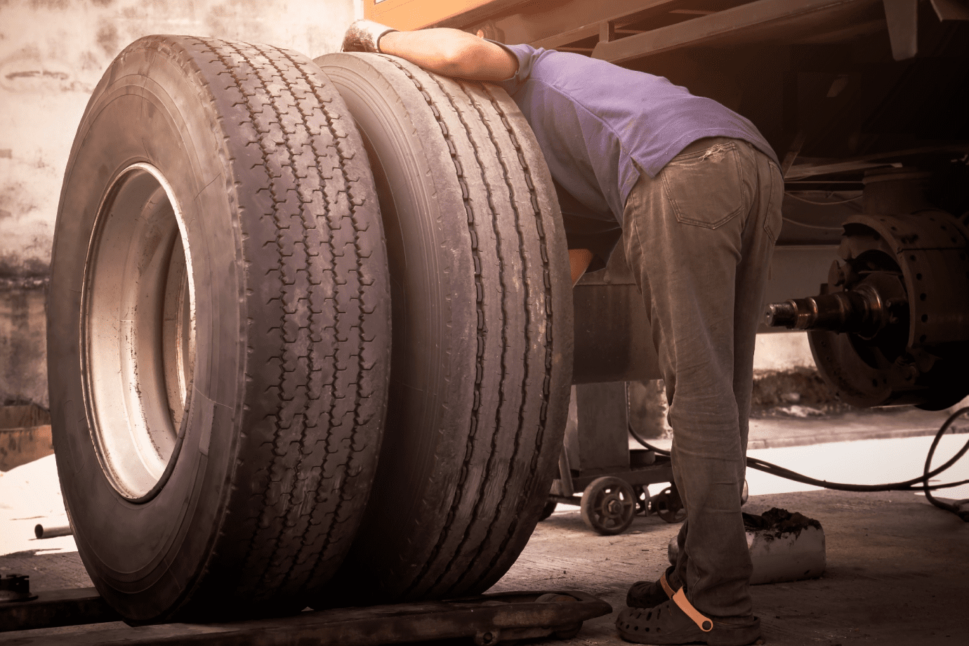 Auto mechanic changing a car tire in auto repair shop. Toned image.<br />
